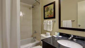 A bathroom with a bathtub, toilet, sink, and a large mirror.