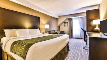 A hotel room with a large bed, a desk, a chair, and a television.