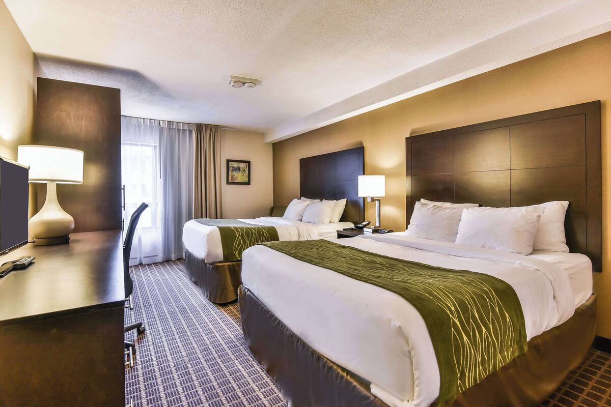 A hotel room with two beds, a desk, and a chair.