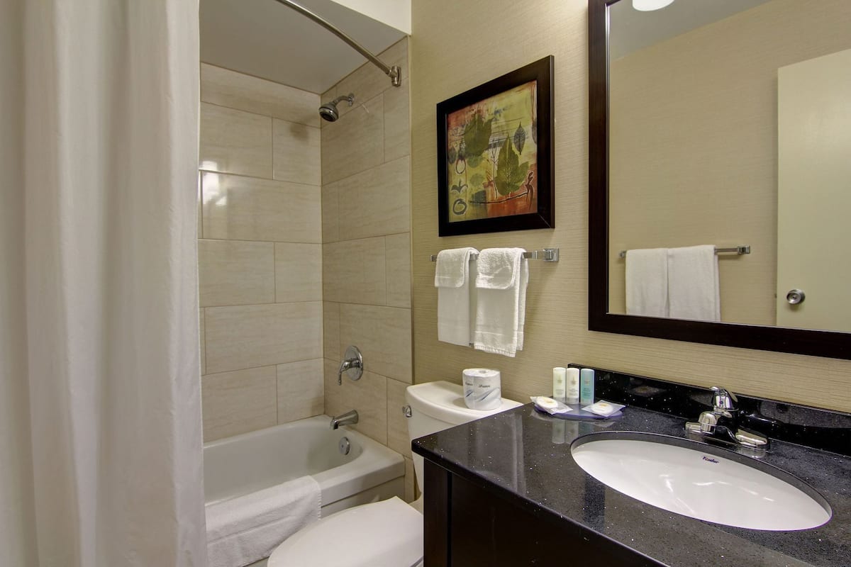 A bathroom with a bathtub, toilet, sink, and a large mirror.