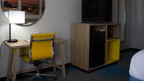 A hotel room with a desk, chair, television, and a minibar. - Days Inn by Wyndham Colby (Colby)
