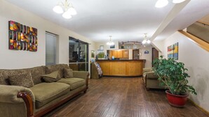 A living room with a wooden floor, a sofa, a coffee table, and a potted plant. - Days Inn by Wyndham Colby (Colby)