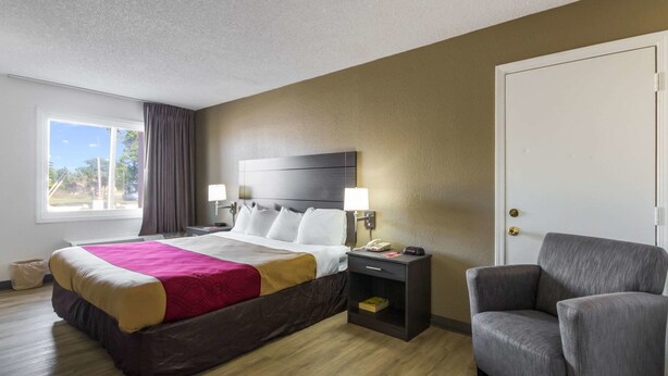 A hotel room with a bed, bedside lamps, a chair, and a nightstand.