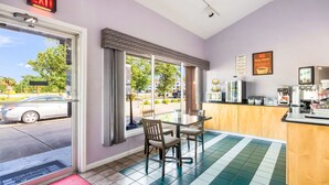 A hotel room with a dining area, a kitchen, and a view of the street.
