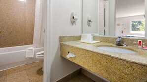 A bathroom with a shower, a sink, a mirror, and a towel rack.