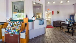 A reception area with a counter, informational brochures, a couch, and a dining area with chairs and a table.