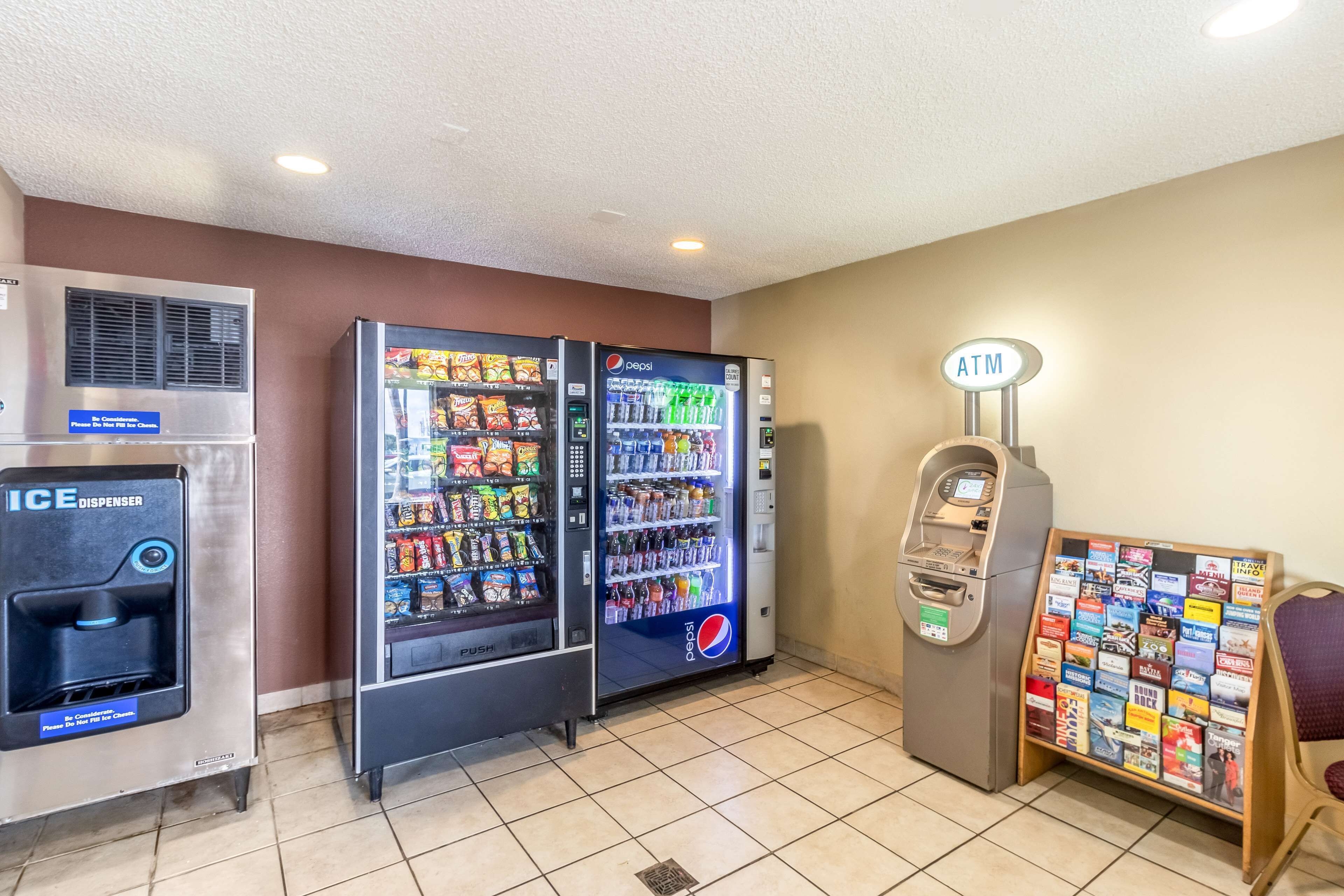 Een automaatruimte met een ijsdispenser, twee Pepsi-automaten, een geldautomaat en een informatiebord voor reizigers.
