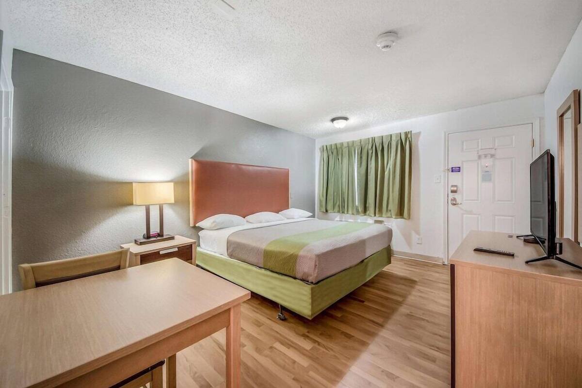 Ein Hotelzimmer mit Bett, Schreibtisch, Fernseher und Tür.