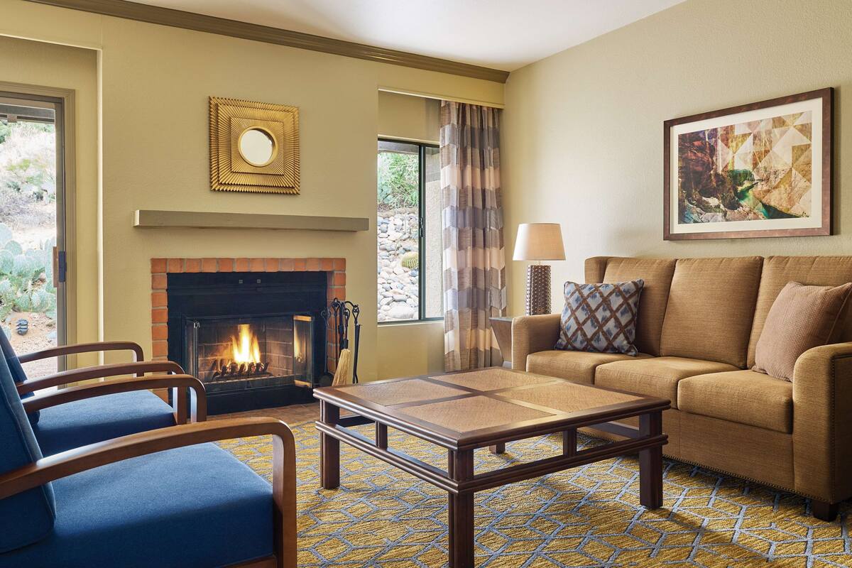 Una sala de estar con chimenea, un sofá, una mesa de centro y un sillón azul.