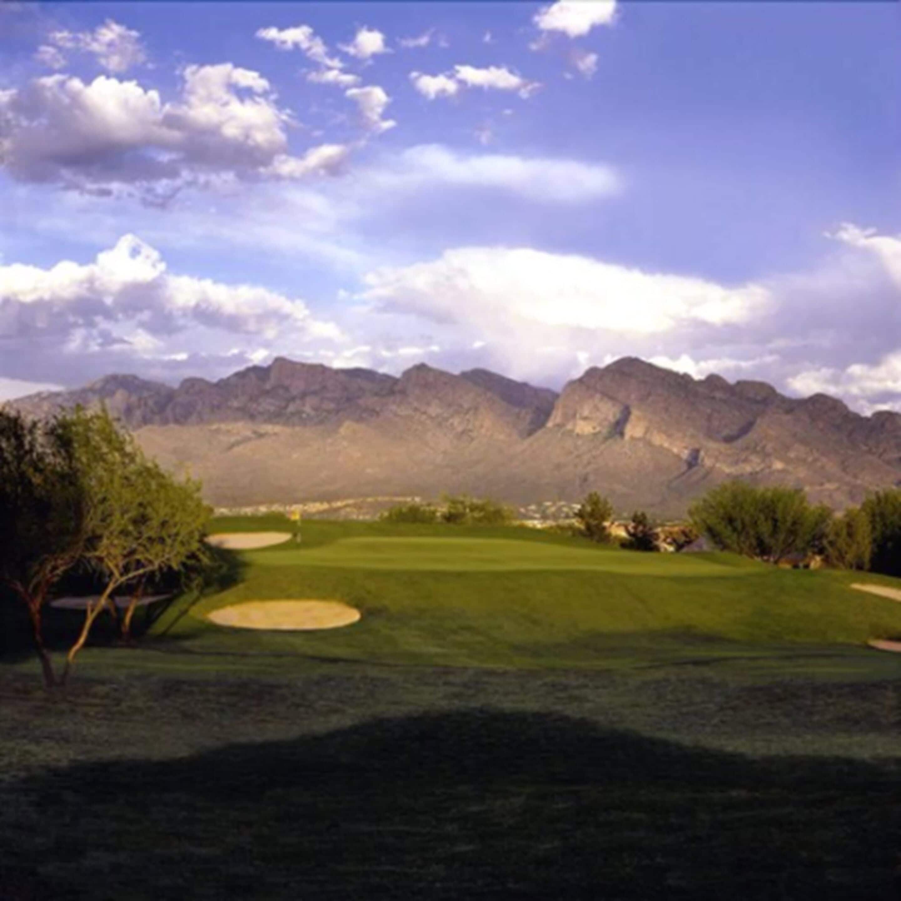 A golf course with a mountain backdrop.