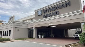 A building with a sign reading 'WYNDHAM GRAND' and a parking area with a flag.
