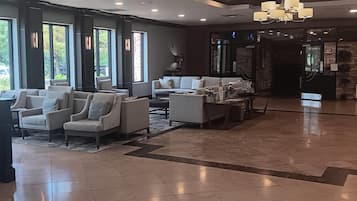 A modern lobby with a seating area, large windows, and a chandelier.