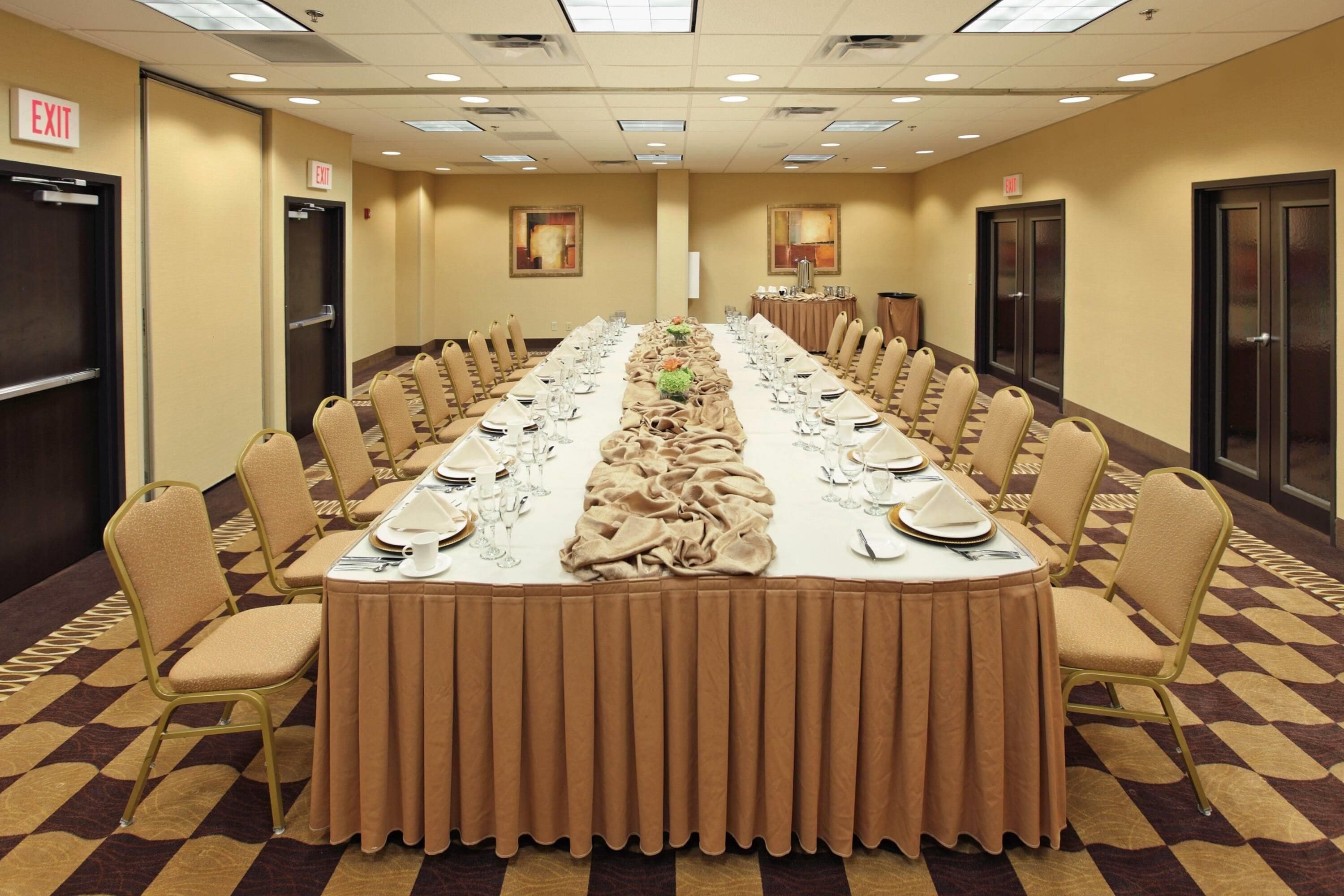 A conference room with a long table set for a meeting, equipped with chairs, tables, and a buffet area.