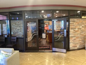 A reception area with a glass door entrance, a seating area with chairs, and a stone wall.