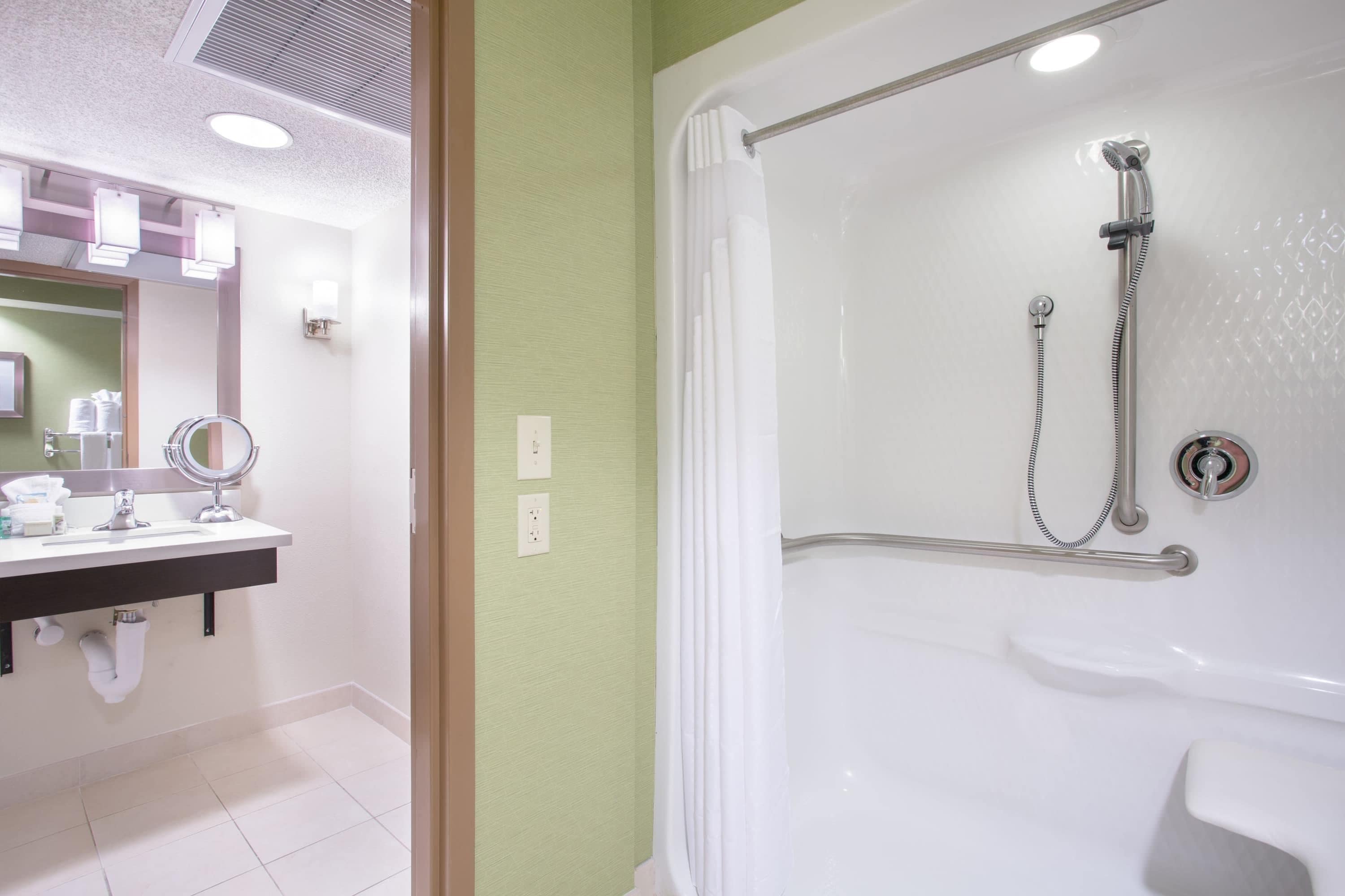 A bathroom with a shower, sink, mirror, and light fixtures.
