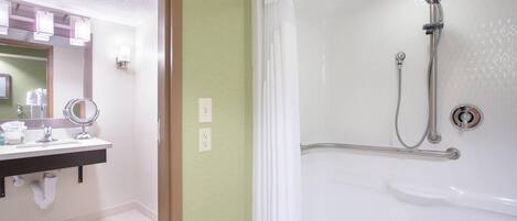 A bathroom with a shower, sink, mirror, and light fixtures.