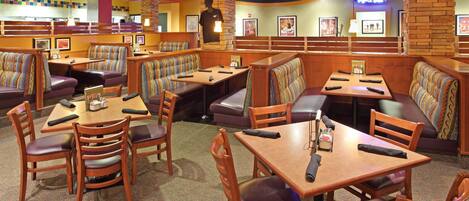A restaurant with booths and tables, some with remote controls on them.