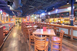 A restaurant with booths, tables, and a bar area. - Wyndham Grand Executive Center Little Rock Airport (Little Rock)