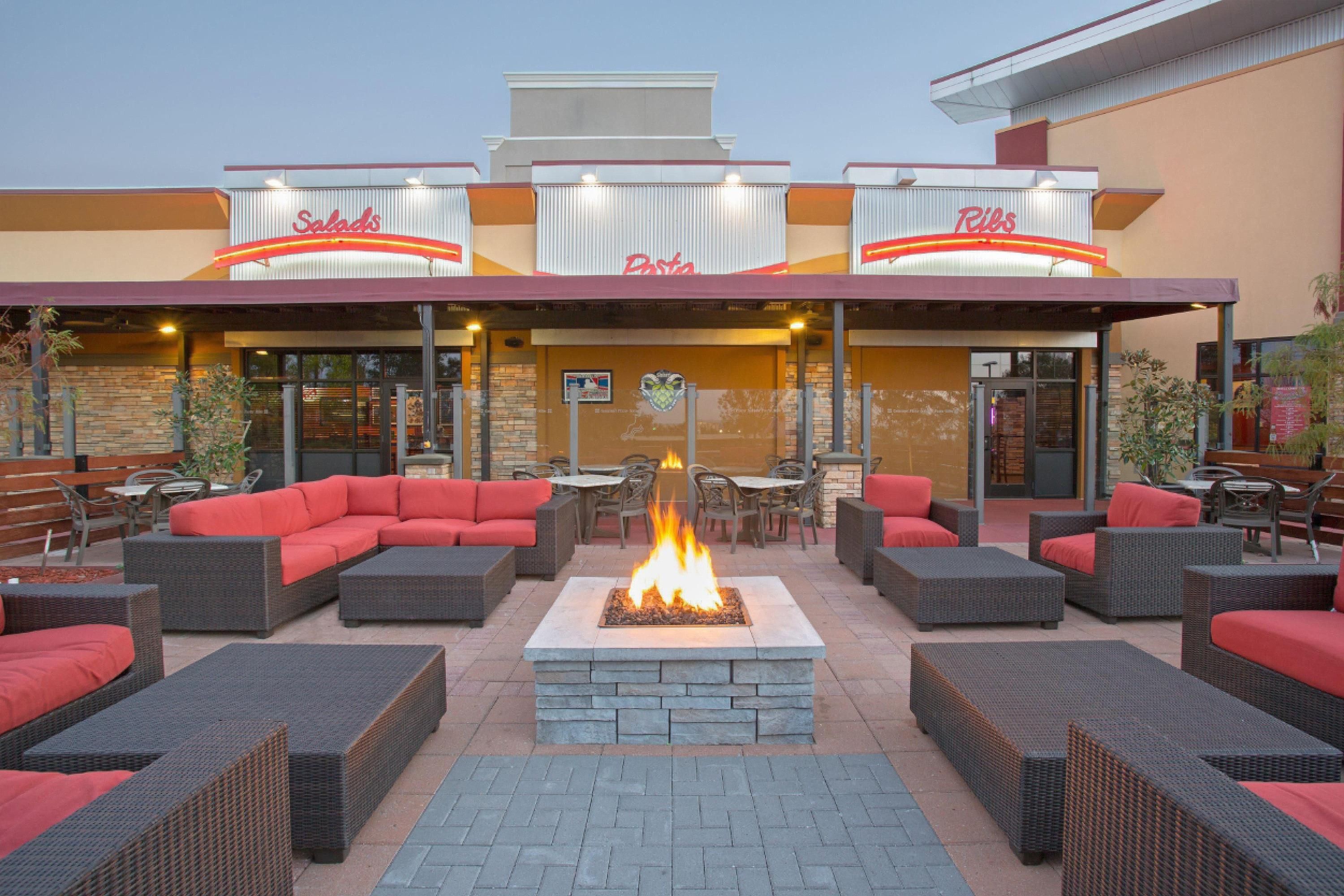 An outdoor seating area with wicker furniture and a central fire feature.