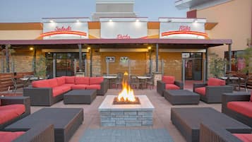 An outdoor seating area with wicker furniture and a central fire feature.