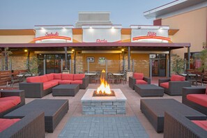 An outdoor seating area with wicker furniture and a central fire feature. - Wyndham Grand Executive Center Little Rock Airport (Little Rock)