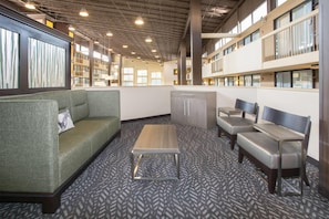 A modern library with a green sofa, a wooden coffee table, and several cushioned chairs. - Wyndham Grand Executive Center Little Rock Airport (Little Rock)