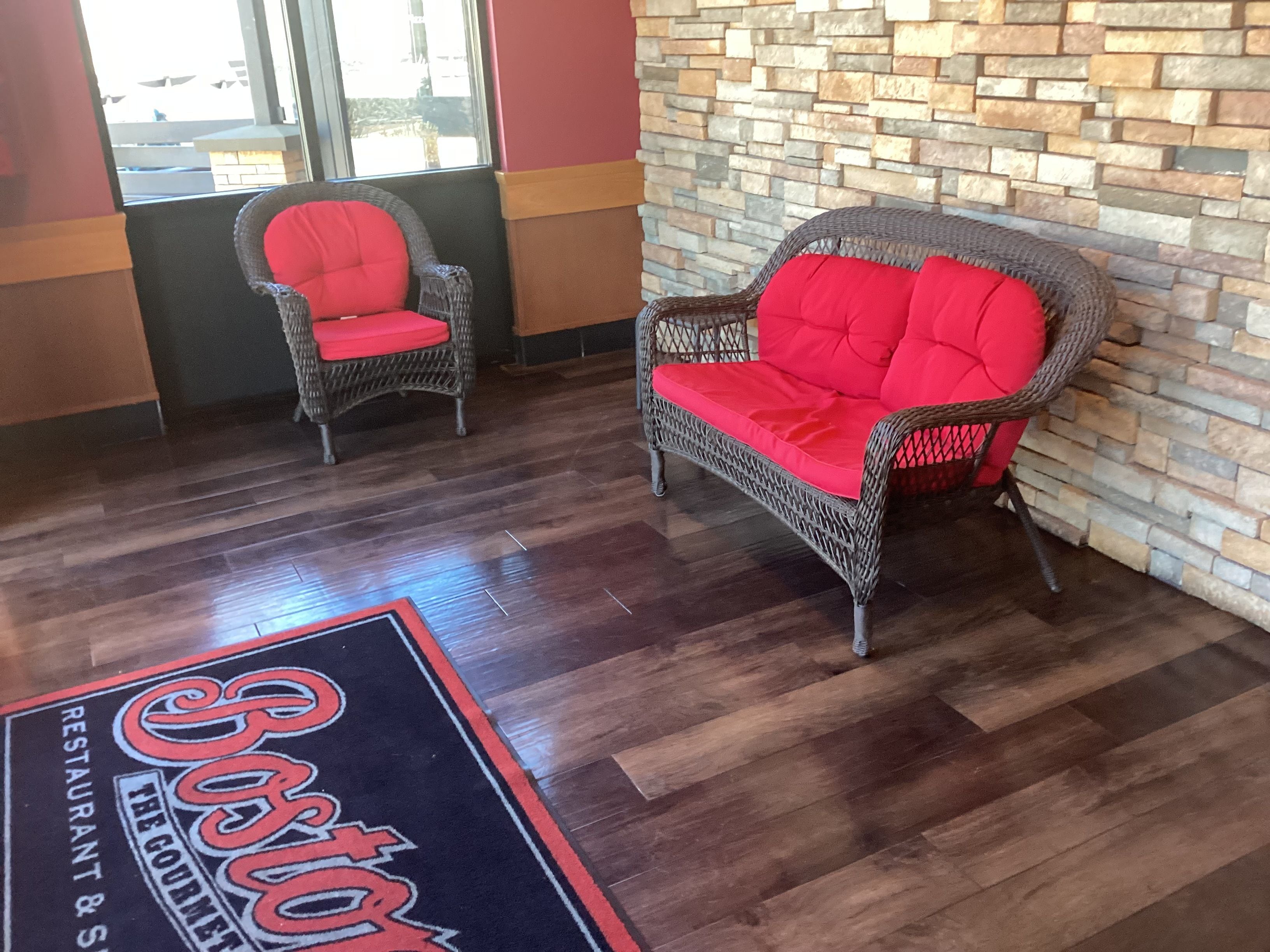 A reception area with wicker furniture and a stone wall.