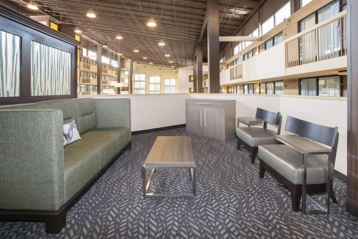 A lobby with a sofa, chairs, a coffee table, and a bookshelf.