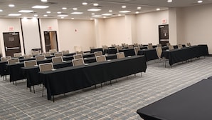 Un salón de conferencias con mesas y sillas dispuestas en filas, y señalización de salida.
