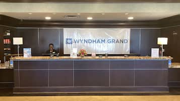 A reception desk with a banner reading 'WYNDHAM GRAND' and a receptionist behind it.