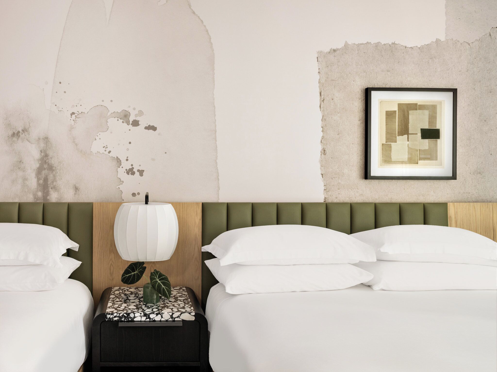 A hotel room with a bed, a nightstand, a lamp, and a framed picture on the wall.