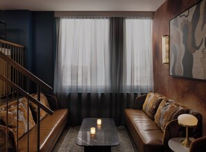 A modern living room with a sofa set, a coffee table, and a staircase. - Kimpton Theta New York - Times Square by IHG (New York)