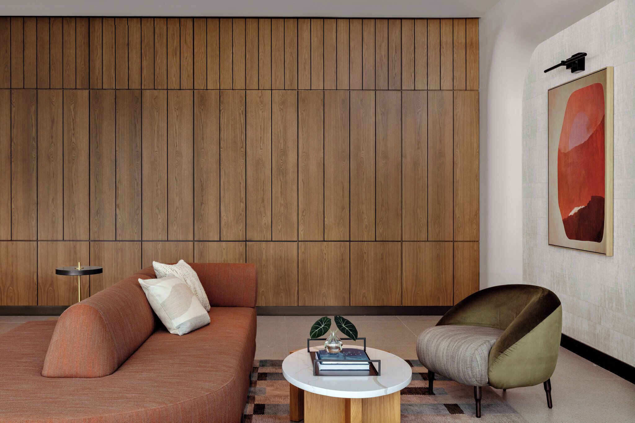 A modern living room with a sofa, armchair, coffee table, and a painting on the wall.
