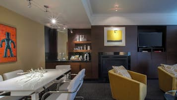 Una habitación de hotel moderna con comedor, sofá, chimenea y televisión.