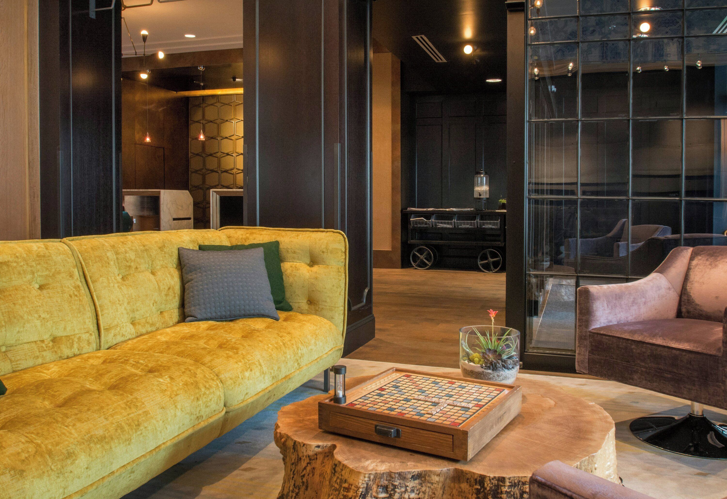 A modern living room with a yellow sofa, a wooden coffee table, and a chessboard.