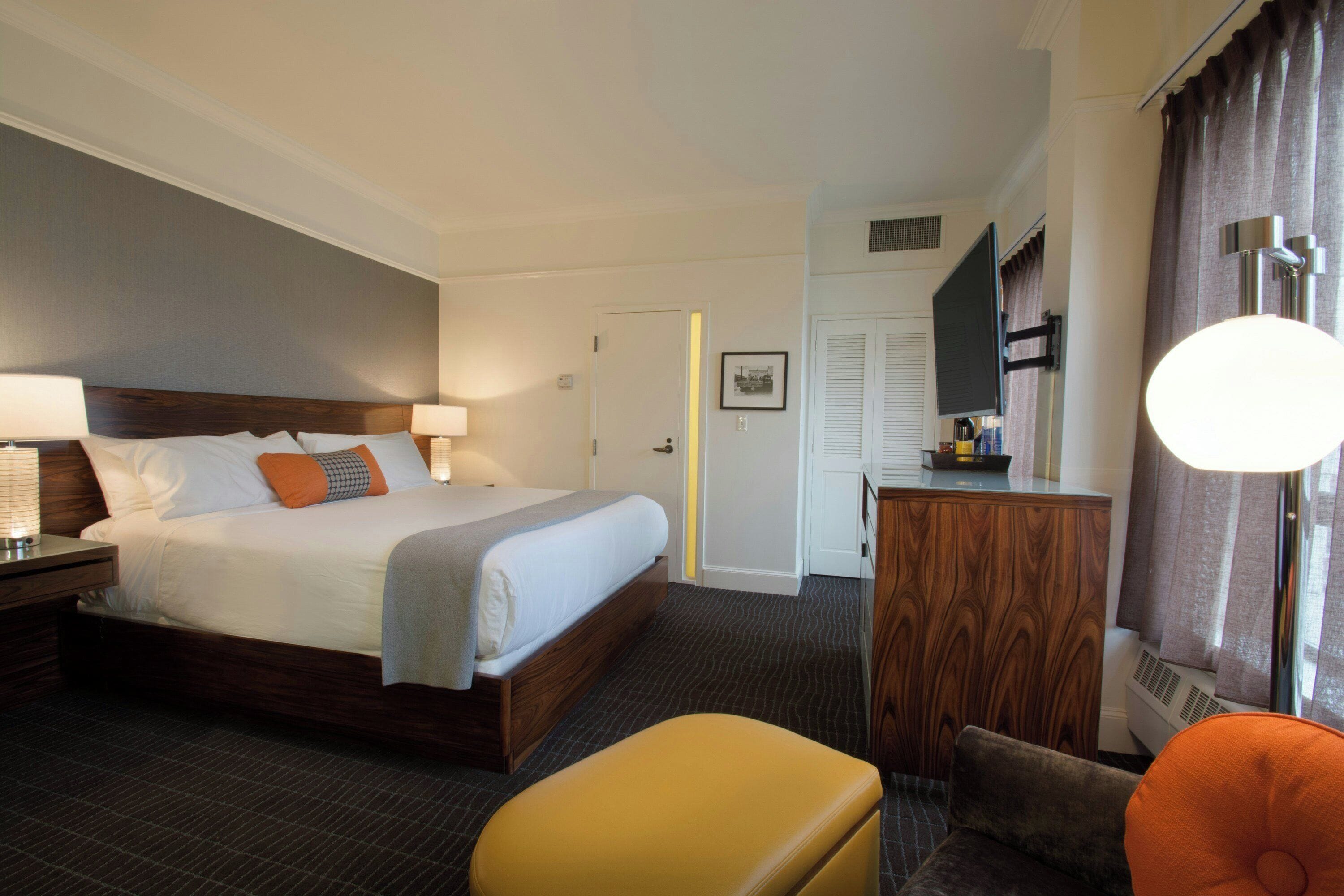 A hotel room with a bed, a desk, a chair, and a wardrobe.