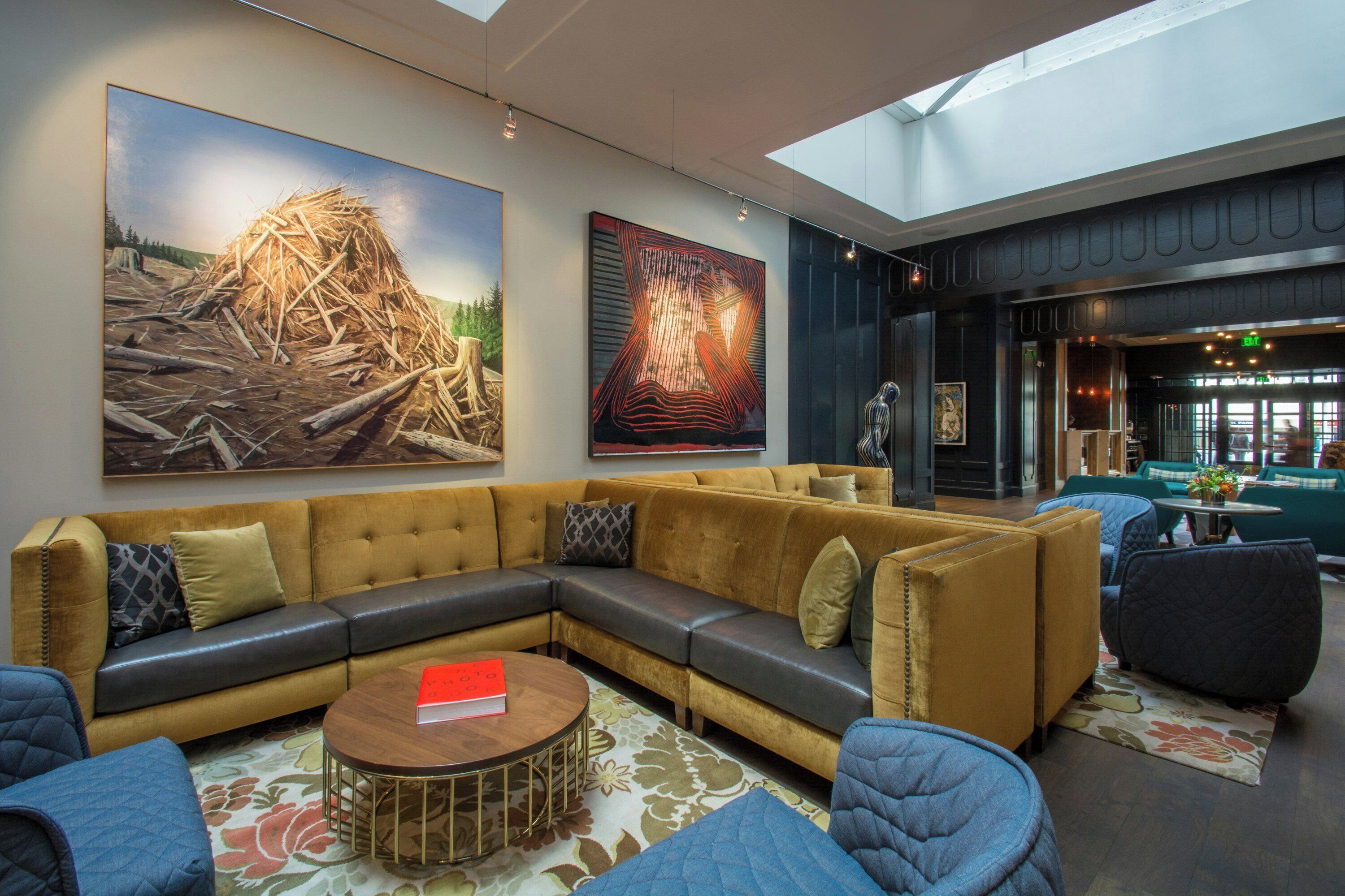A modern lounge area with a sectional sofa, round coffee table, and a large painting on the wall.