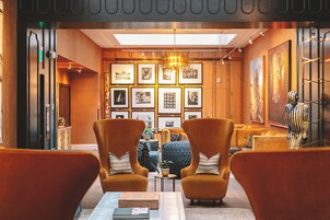 Un área de estar moderna con una mesa central, dos sillones y una pared de fotografías enmarcadas.
