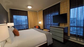 A hotel room with a large bed, a flat-screen TV mounted on the wall, a desk, and a chair.
