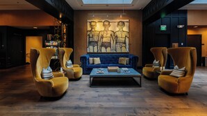 Eine Lobby mit einem blauen Sofa, zwei gelben Sesseln, einem Couchtisch und einem großen abstrakten Gemälde an der Wand.