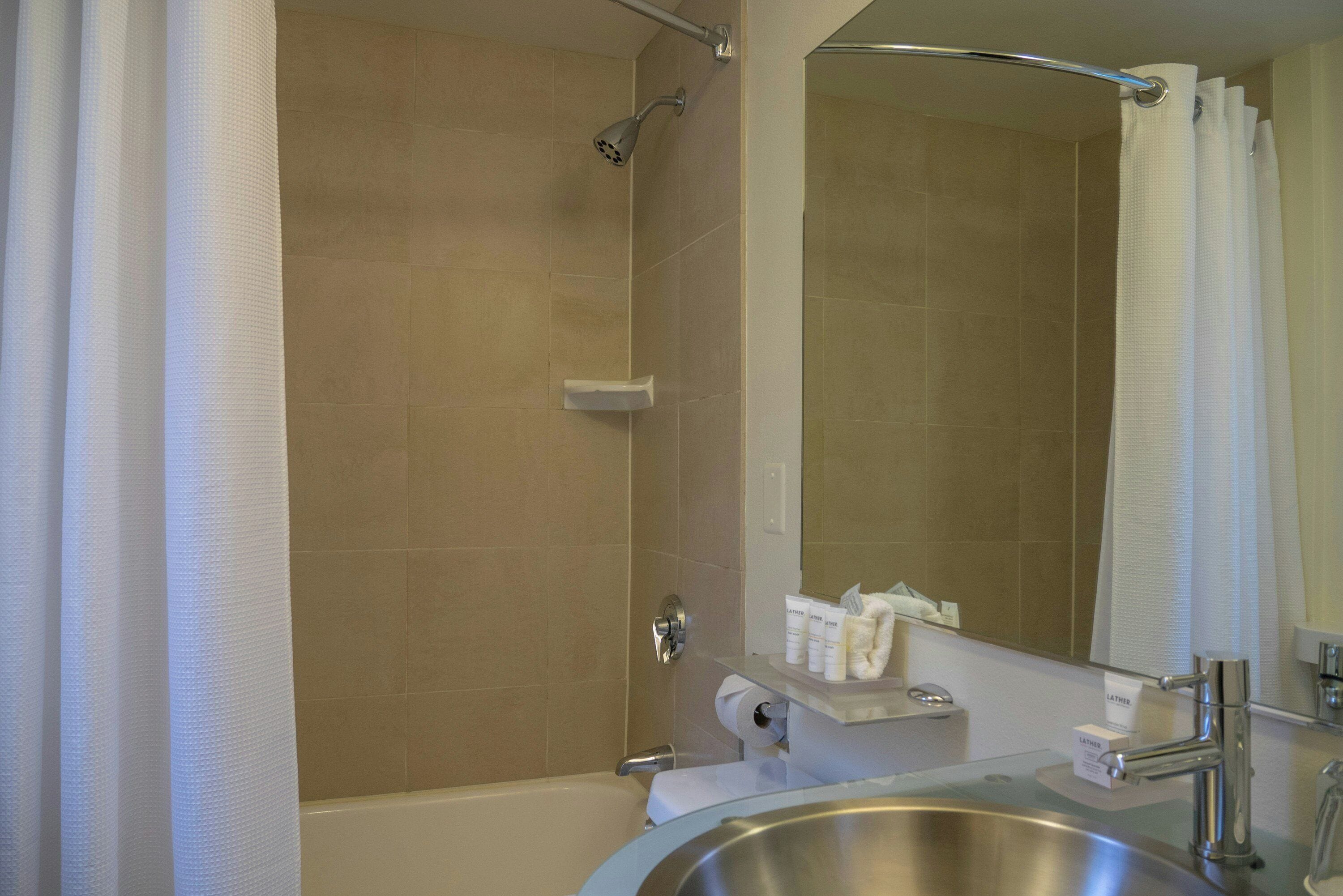 A bathroom with a bathtub, a shower, a toilet, a sink, and a mirror.