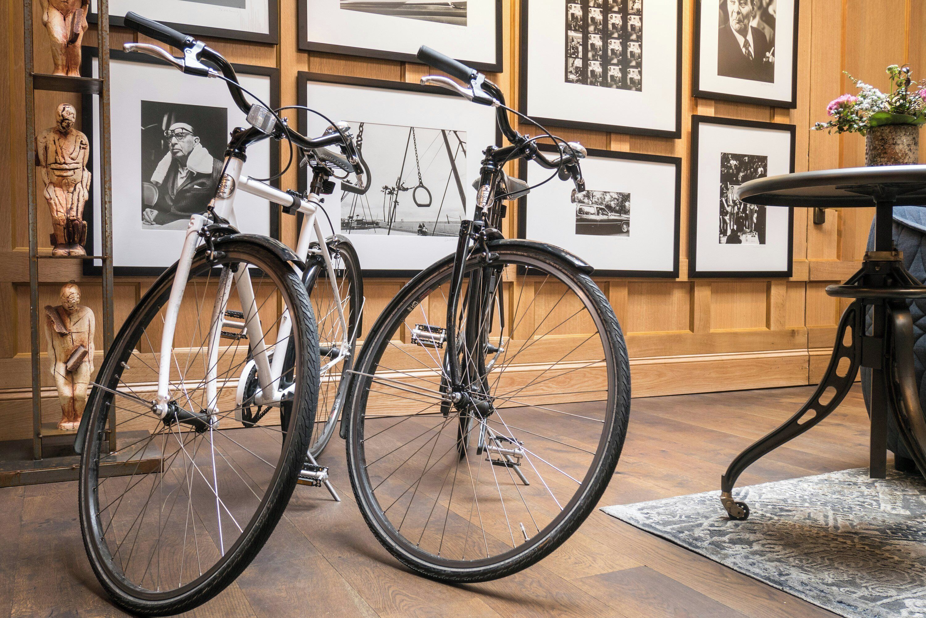 A room with two bicycles, wooden panel walls, and framed pictures.