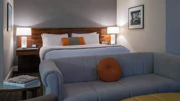 Une chambre d’hôtel avec un lit, deux lampes de chevet, une table de chevet, un canapé et un tableau encadré au mur.