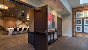 Eine moderne Hotelhalle mit Essbereich, einer Rezeption und einer Wand mit gerahmten Fotografien.