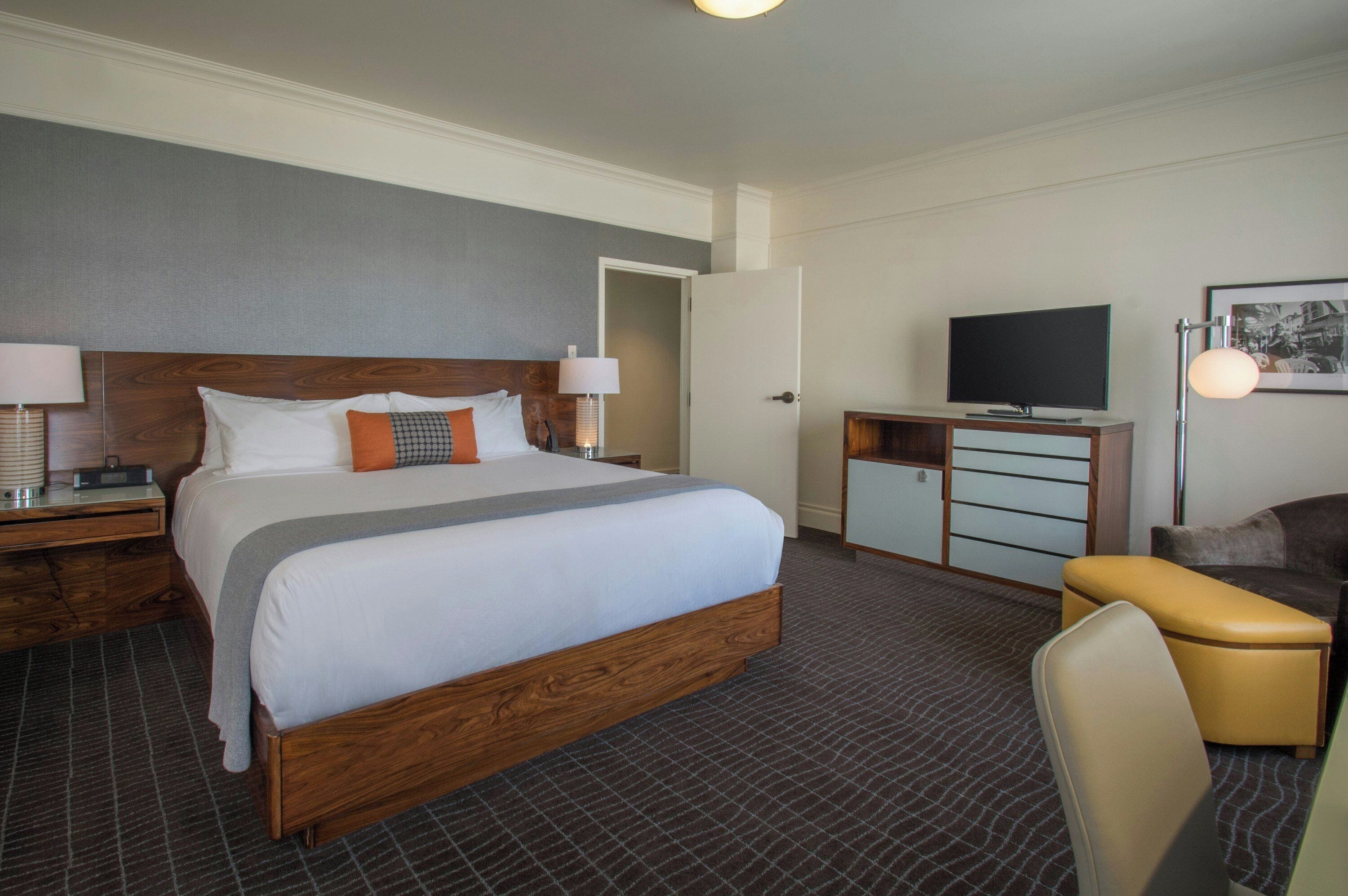 A hotel room with a large bed, a television, a desk, and a chair.