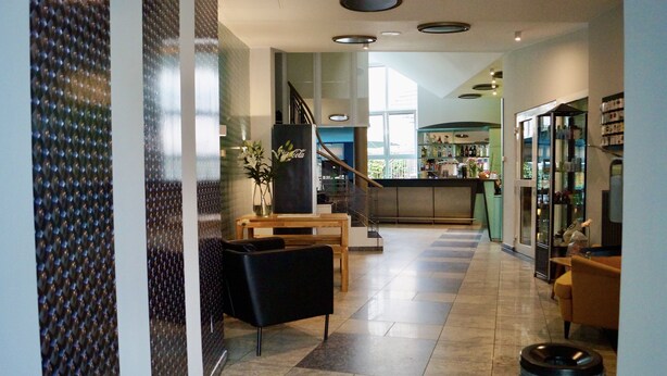 A modern hotel lobby with a staircase, seating area, and a bar. - Grand Hostel Berlin Urban (Berlin)