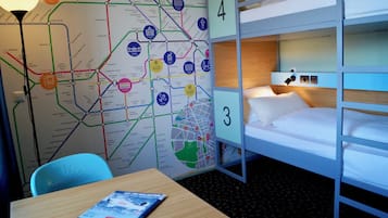 Quarto de hotel com beliches, um mapa da cidade e uma mesa com uma revista.