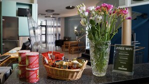A hotel reception area with a counter displaying snacks, a vase with flowers, and a sign offering free WiFi. - Grand Hostel Berlin Urban (Berlin)