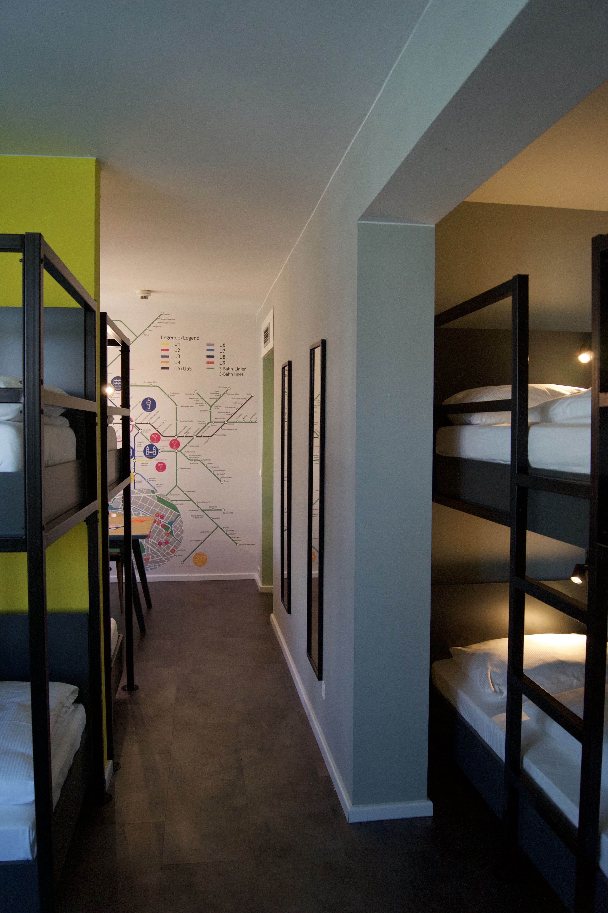 Un pasillo estrecho con literas a ambos lados, una pared con un mapa y su explicación, y una puerta al final.
