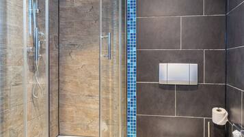 A bathroom with a glass-enclosed shower, a toilet, and a bidet.